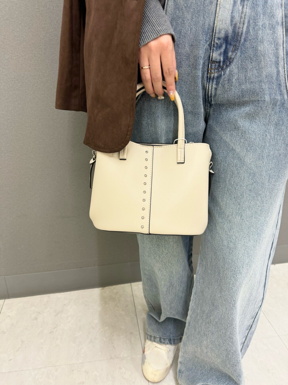 グレー系のニット/セーター、ブルー系のデニムパンツ、ブラウン系のその他アウターを着用したレディースの秋コーディネートの2枚目の写真