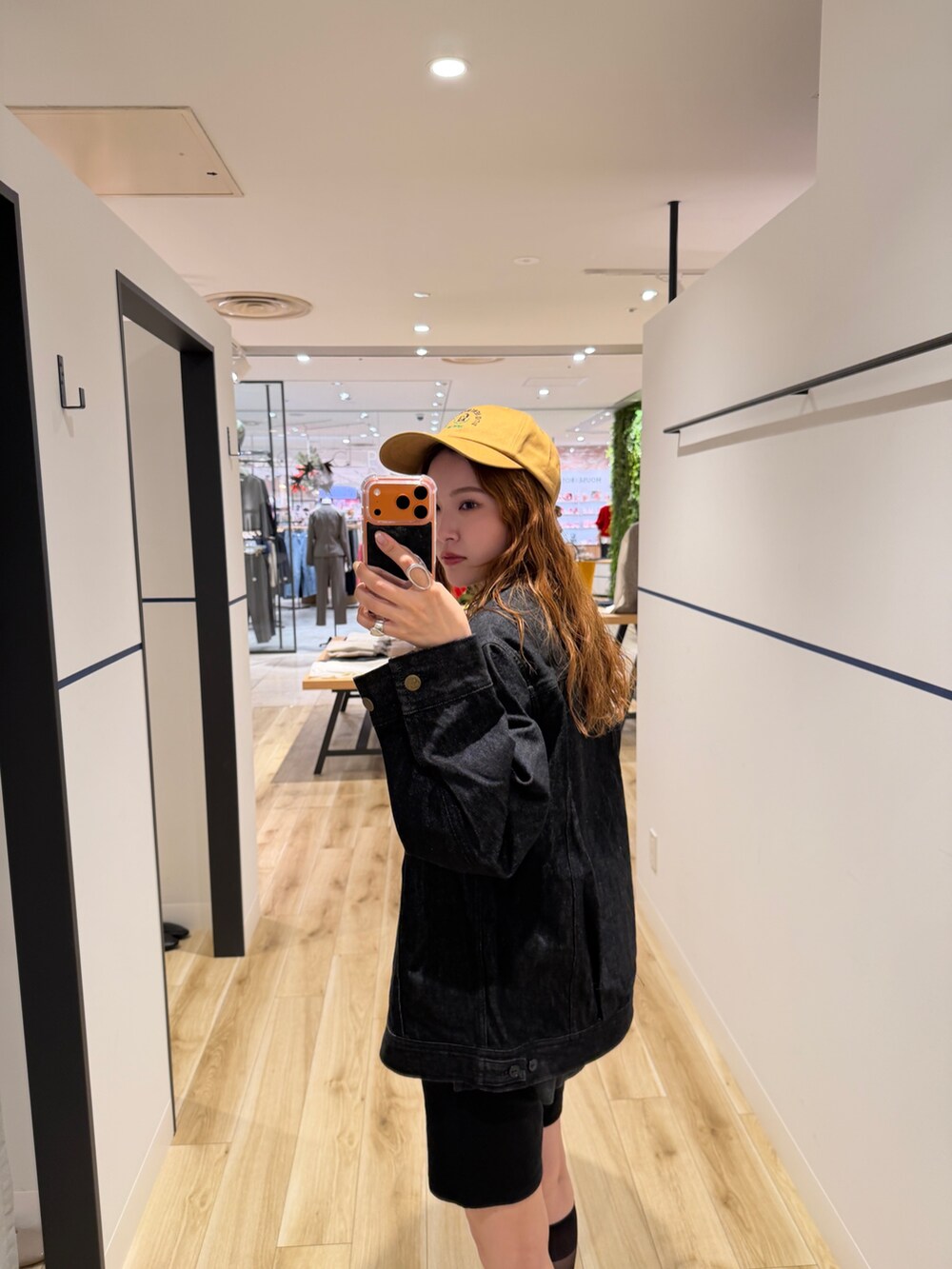 ブルー系のデニムジャケット、グリーン系のニット/セーター、ブラウン系のスニーカーを着用したレディースの秋コーディネートの3枚目の写真