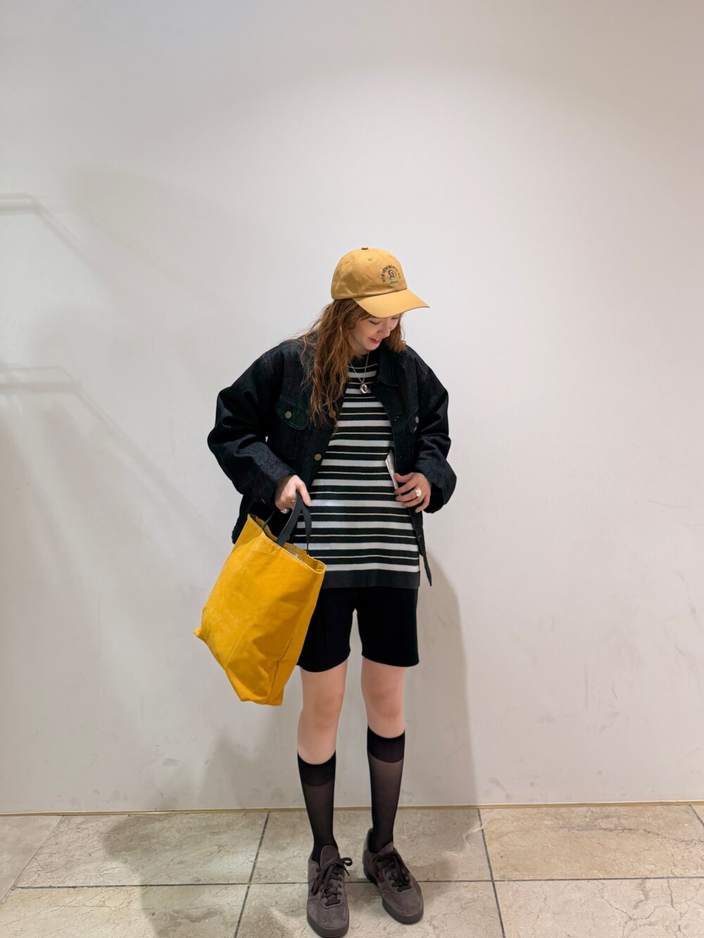 ブルー系のデニムジャケット、グリーン系のニット/セーター、ブラウン系のスニーカーを着用したレディースの秋コーディネートの2枚目の写真