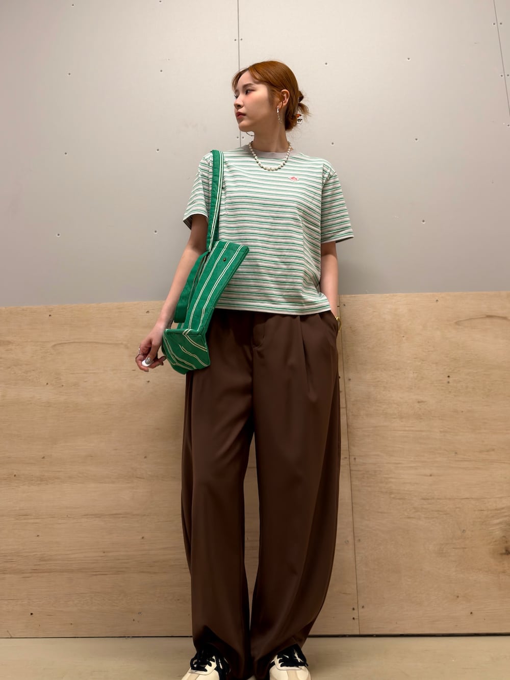 グリーン系のトートバッグ、ベージュ系のスニーカー、グリーン系のTシャツ/カットソーを着用したレディースの春コーディネートの3枚目の写真