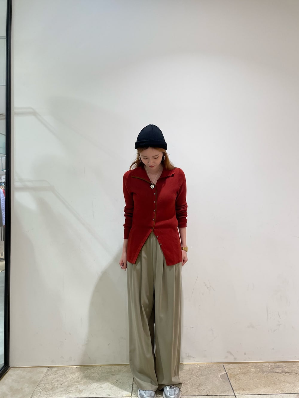 レッド系のニット/セーター、ベージュ系のその他パンツ、ブラック系のニットキャップ/ビーニーを着用したレディースの秋コーディネートの2枚目の写真
