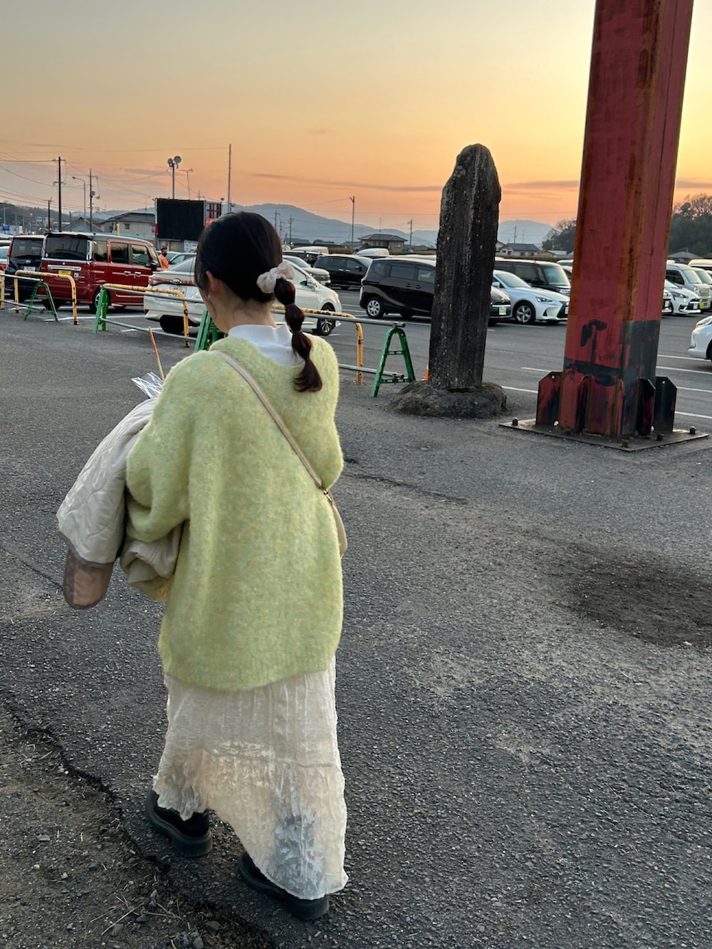 グリーン系のニット/セーター、ホワイト系のワンピース、ブラック系のシューズを着用したレディースの春コーディネートの2枚目の写真