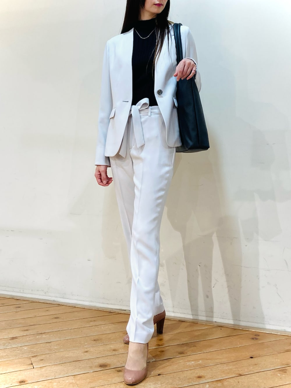 グレー系のスーツジャケット、グレー系のスーツパンツ、ブラック系のトートバッグを着用したレディースの春コーディネートの2枚目の写真