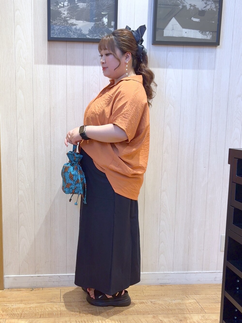 オレンジ系のシャツ/ブラウス、ブルー系のショルダーバッグ、ブルー系のスカートを着用したレディースの夏コーディネートの2枚目の写真