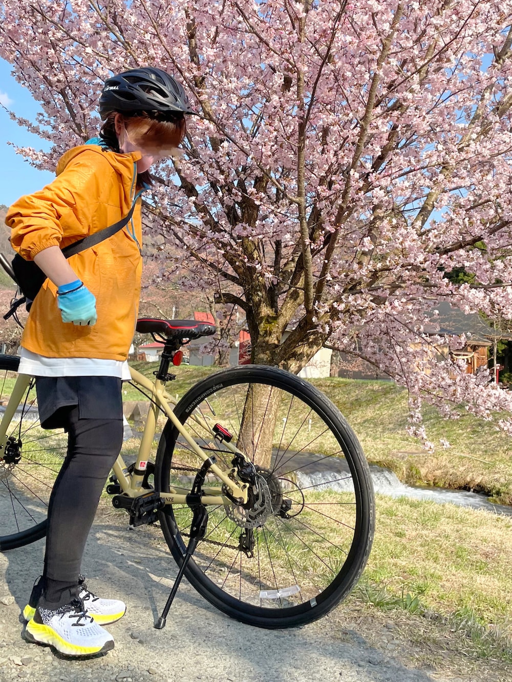 オレンジ系のナイロンジャケット、イエロー系のスニーカー、ブラック系のアウトドア/スポーツを着用したレディースの春コーディネートの2枚目の写真