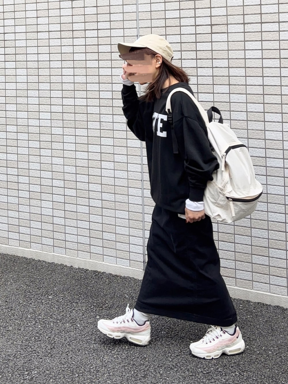 ブラック系のスウェット、ホワイト系のバックパック/リュック、ブラック系のスカートを着用したレディースの冬コーディネートの3枚目の写真