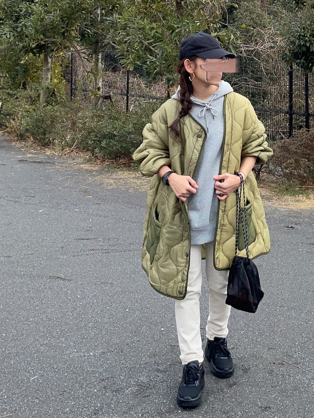 グレー系のパーカー、グリーン系のミリタリージャケット、ベージュ系のデニムパンツを着用したレディースの冬コーディネートの2枚目の写真