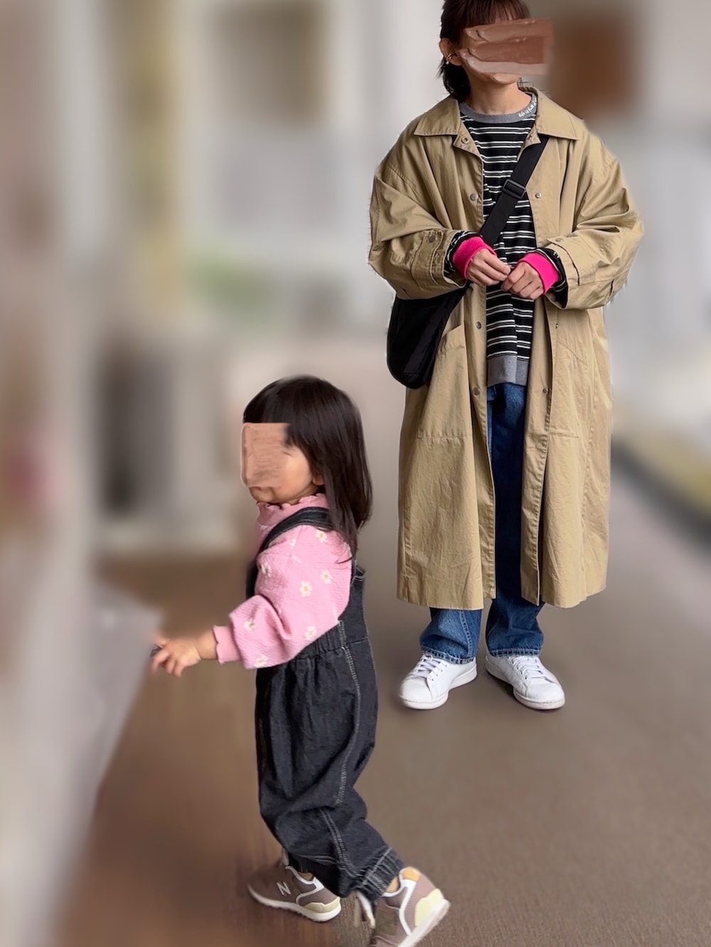 ベージュ系のステンカラーコート、ブラック系のTシャツ/カットソー、ブルー系のデニムパンツを着用したレディースの春コーディネートの2枚目の写真