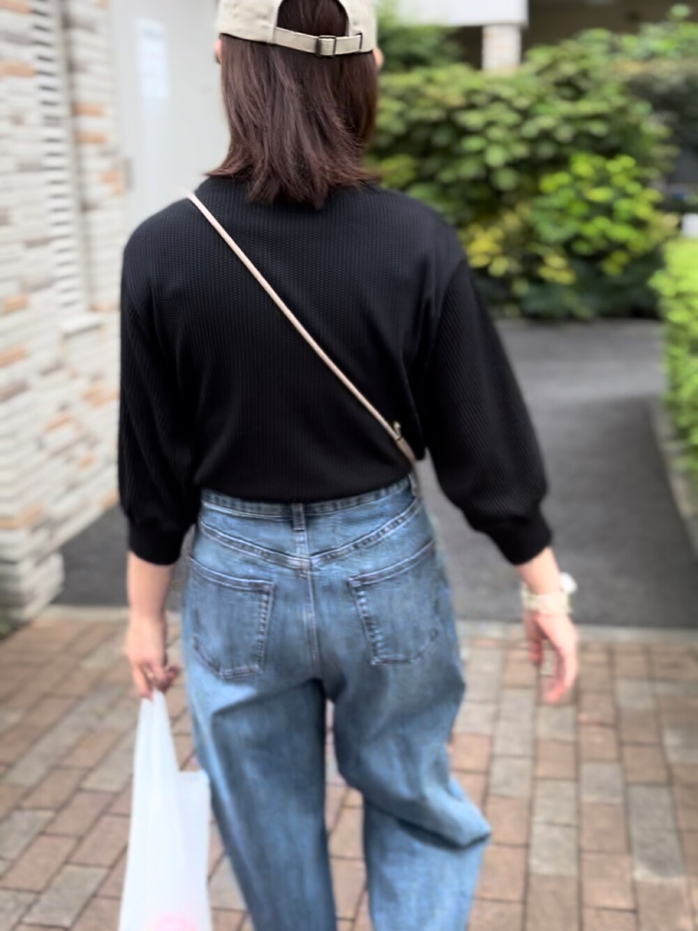 ブラック系のTシャツ/カットソー、ブルー系のデニムパンツ、グリーン系のスニーカーを着用したレディースの秋コーディネートの2枚目の写真