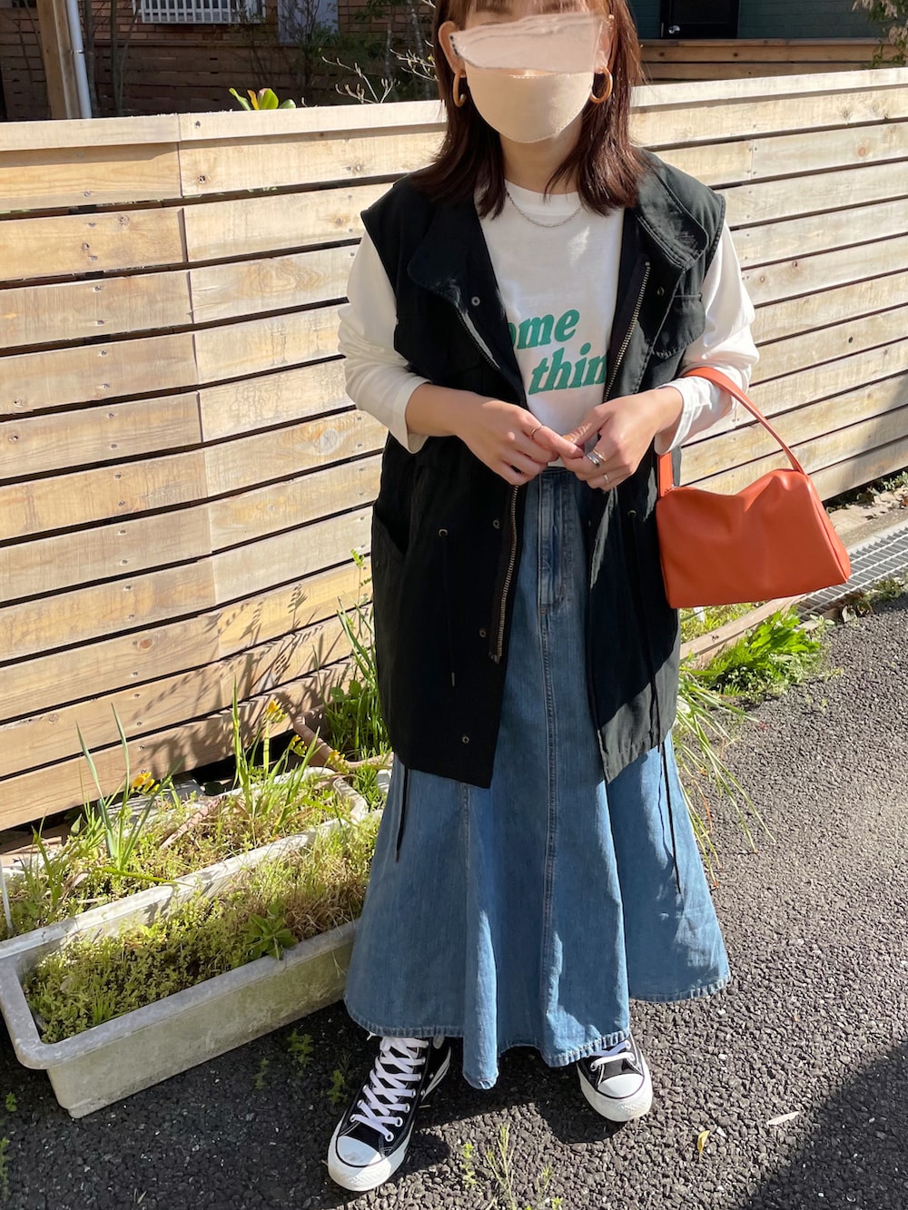 ホワイト系のTシャツ/カットソー、ブラック系のベスト、ブルー系のデニムスカートを着用したレディースの春コーディネートの2枚目の写真