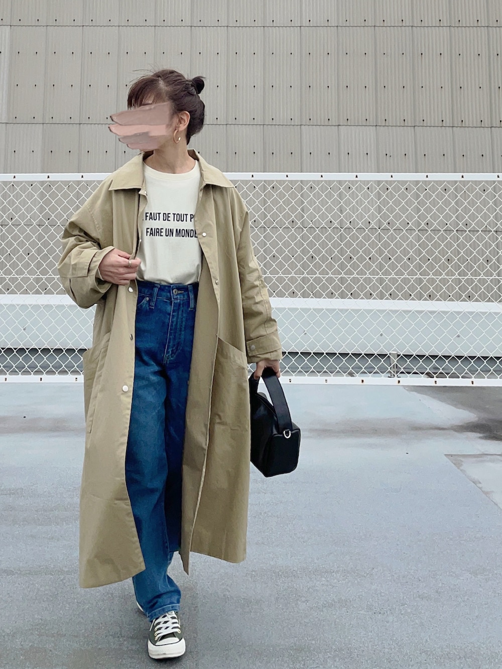 ベージュ系のステンカラーコート、イエロー系のTシャツ/カットソー、ブルー系のデニムパンツを着用したレディースの春コーディネートの2枚目の写真