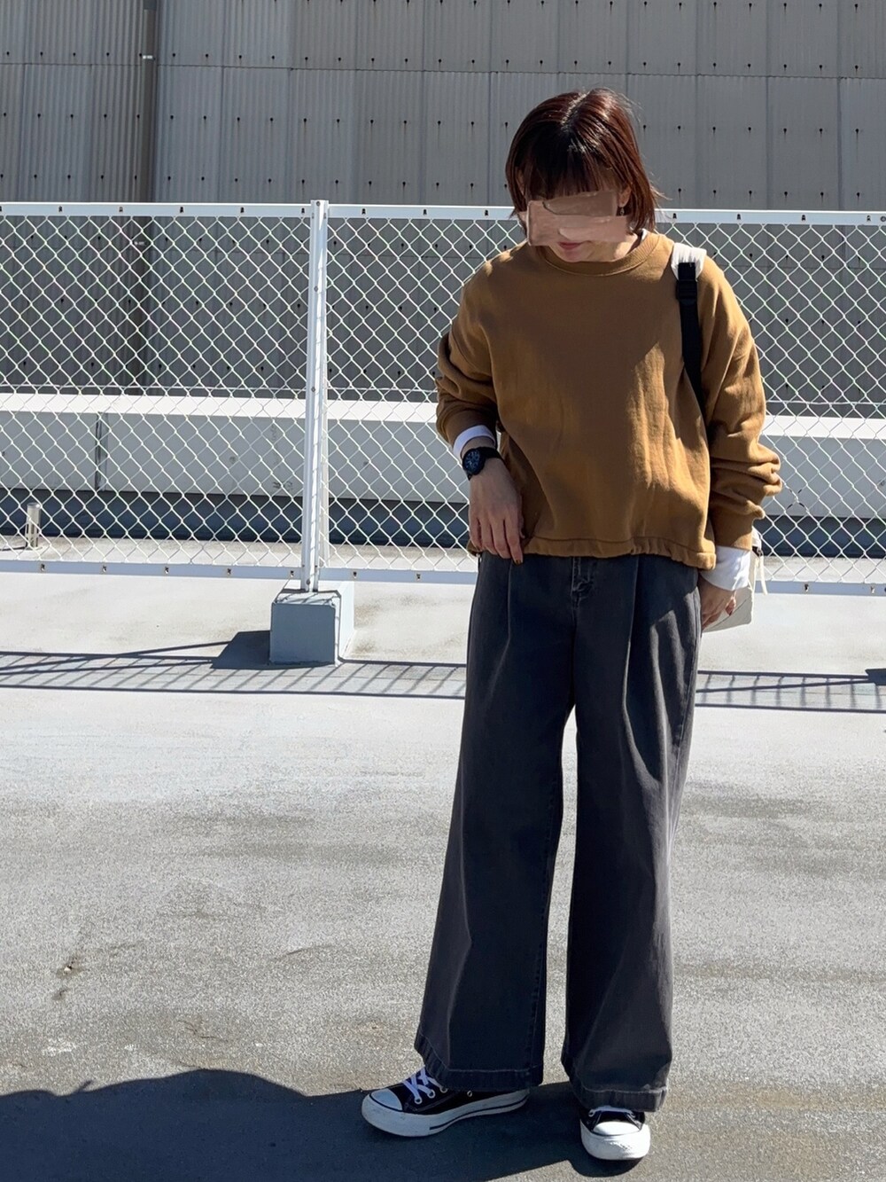 イエロー系のスウェット、ホワイト系のバックパック/リュック、ブラック系のパンツを着用したレディースの冬コーディネートの2枚目の写真