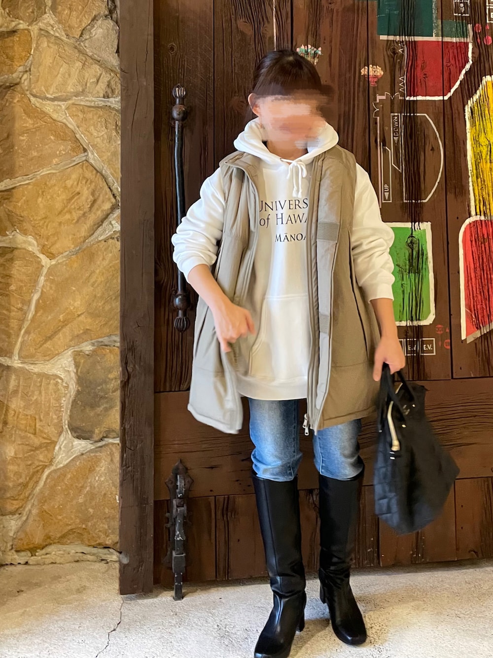 ベージュ系のダウンベスト、ホワイト系のTシャツ/カットソー、ブラック系のハンドバッグを着用したレディースの冬コーディネートの2枚目の写真