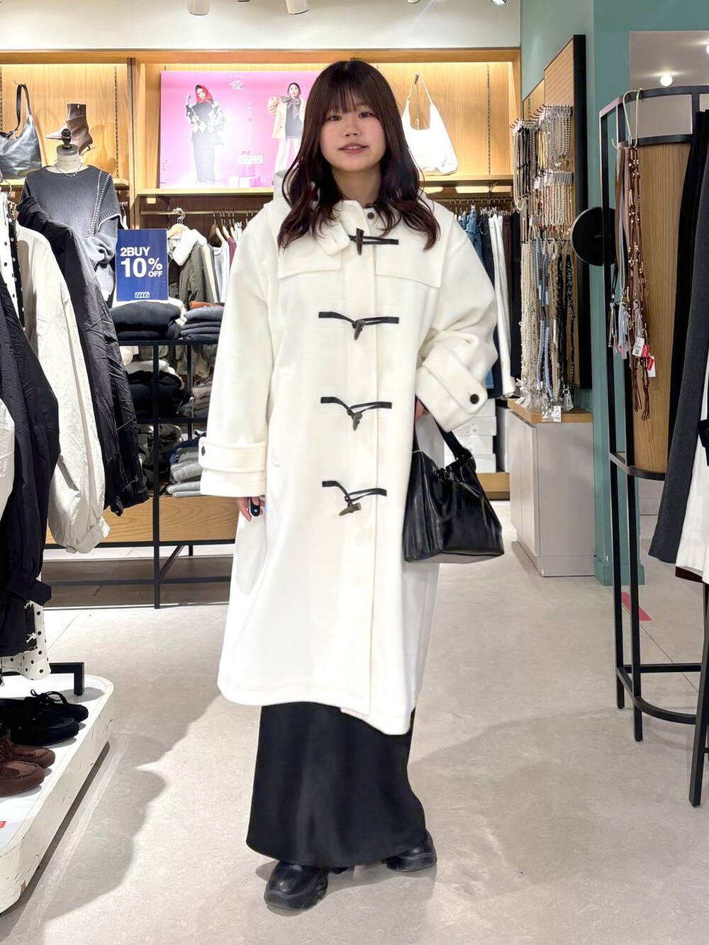 ブラック系のブーツ、ブラック系のスカート、ホワイト系のダッフルコートを着用したレディースの冬コーディネートの2枚目の写真