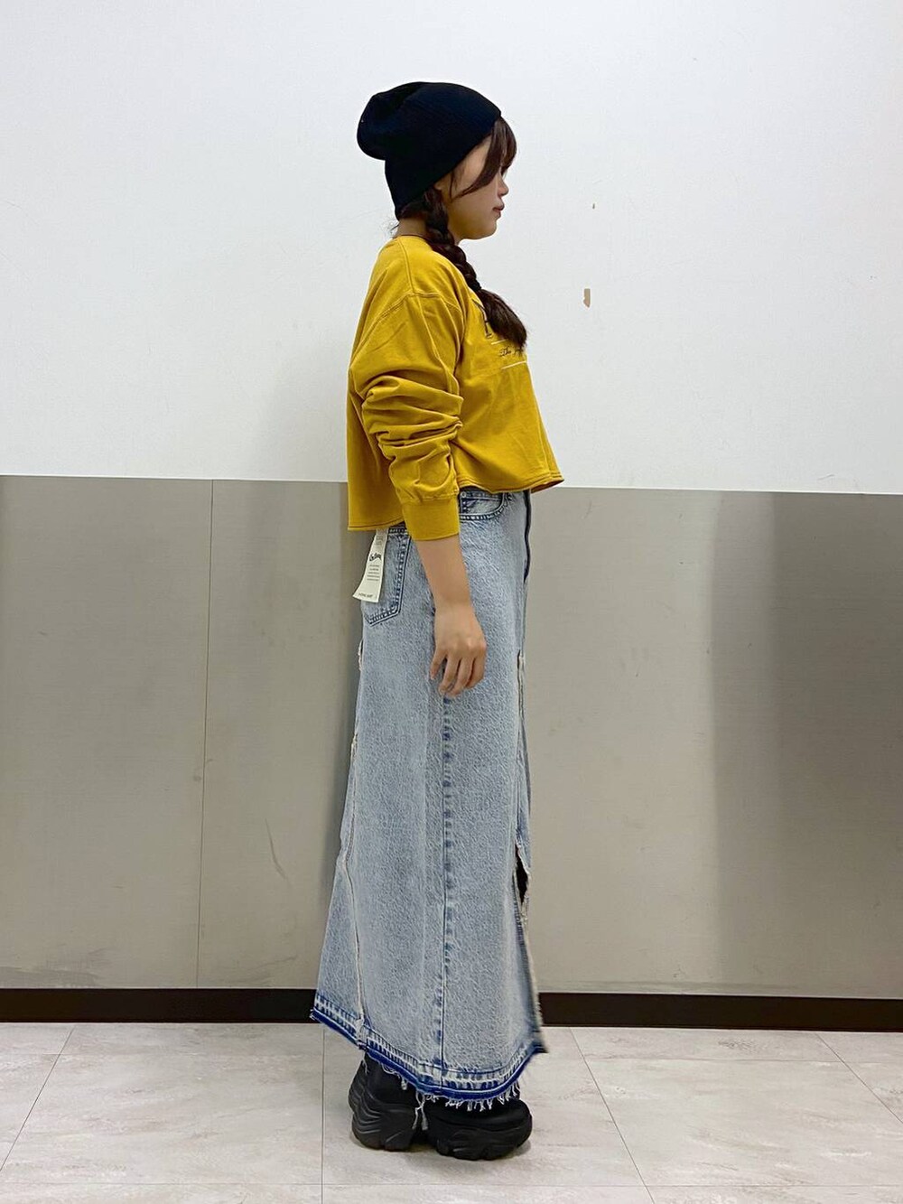 ブルー系のスカート、ブラック系のボディバッグ/ウエストポーチ、ブラック系のブーツを着用したレディースの秋コーディネートの2枚目の写真