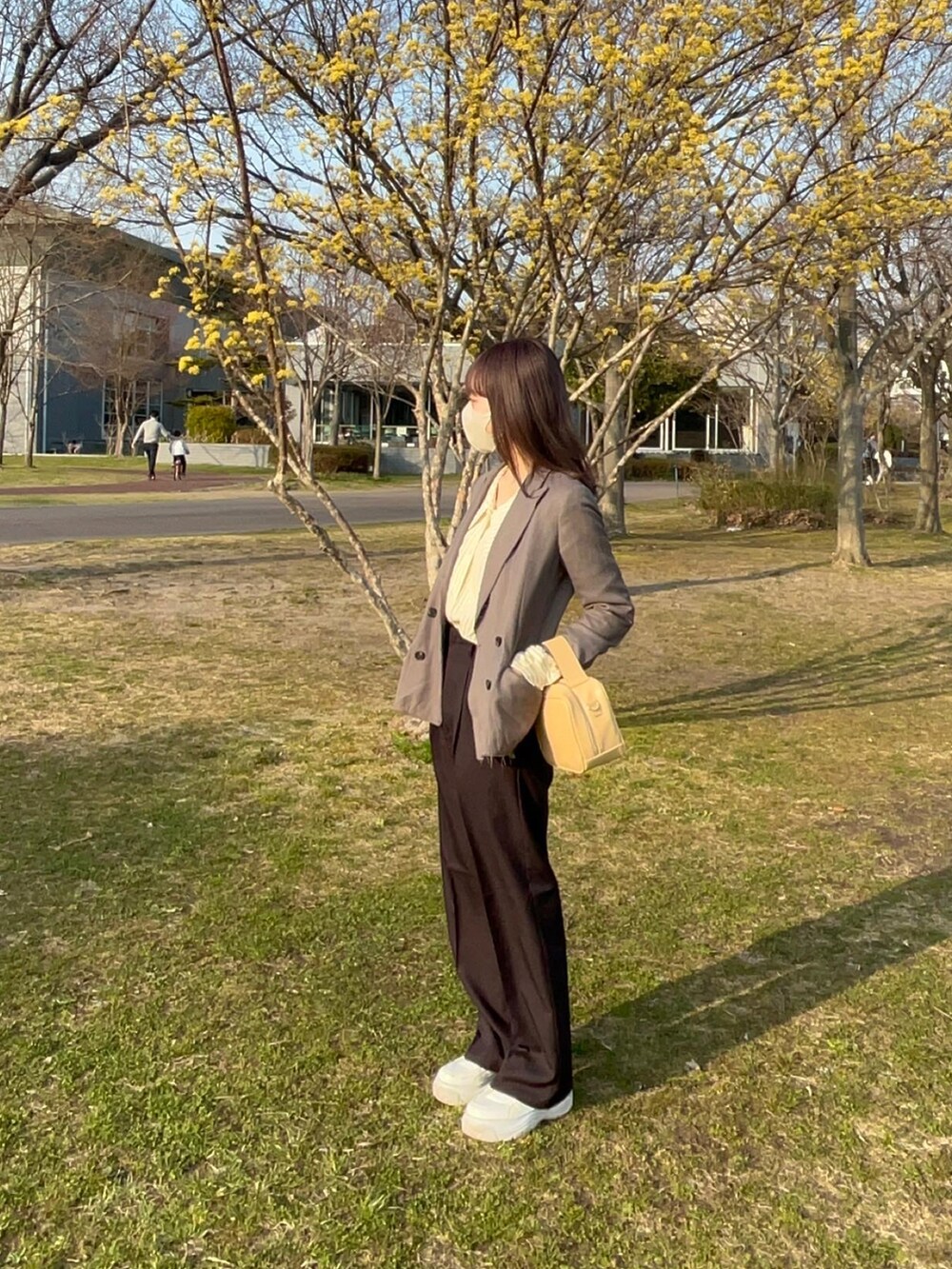 イエロー系のシャツ/ブラウス、ブラック系のスラックス、イエロー系のボストンバッグを着用したレディースの春コーディネートの2枚目の写真