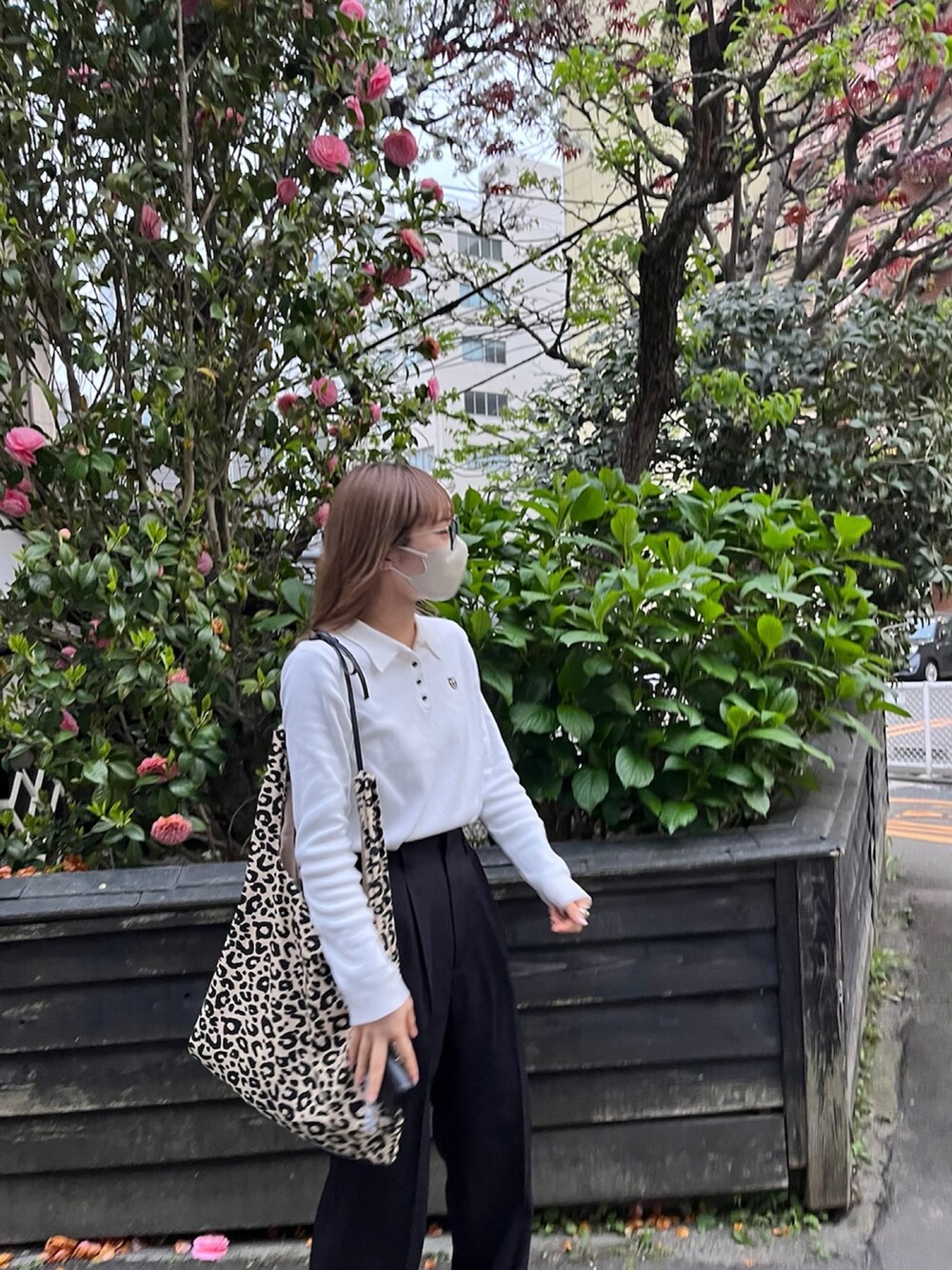 その他のトートバッグ、ホワイト系のポロシャツ、ブラック系のスラックスを着用したレディースの春コーディネートの2枚目の写真