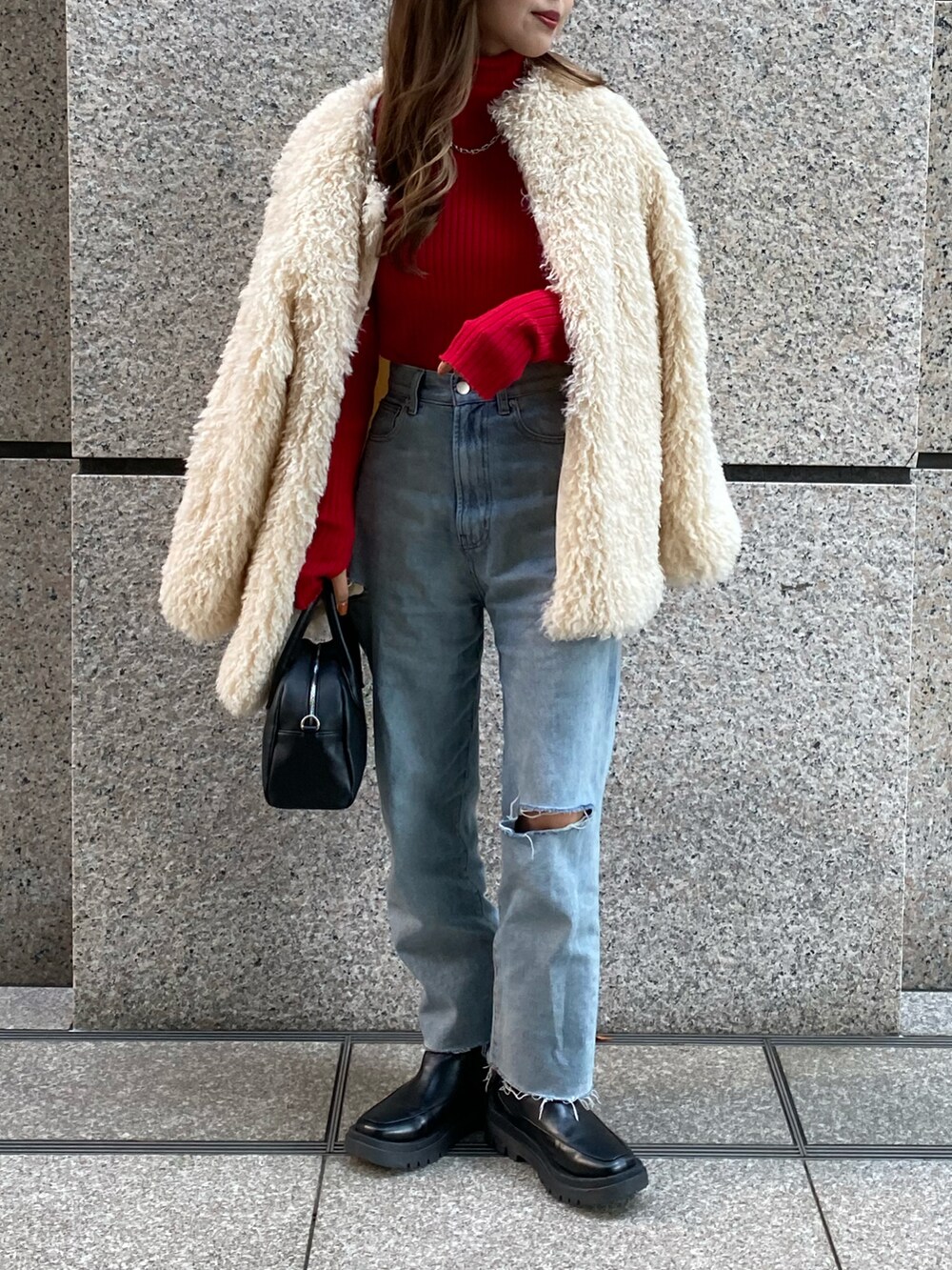 ブラック系のブーツ、ブルー系のデニムパンツ、ブラック系のボストンバッグを着用したレディースの秋コーディネートの2枚目の写真