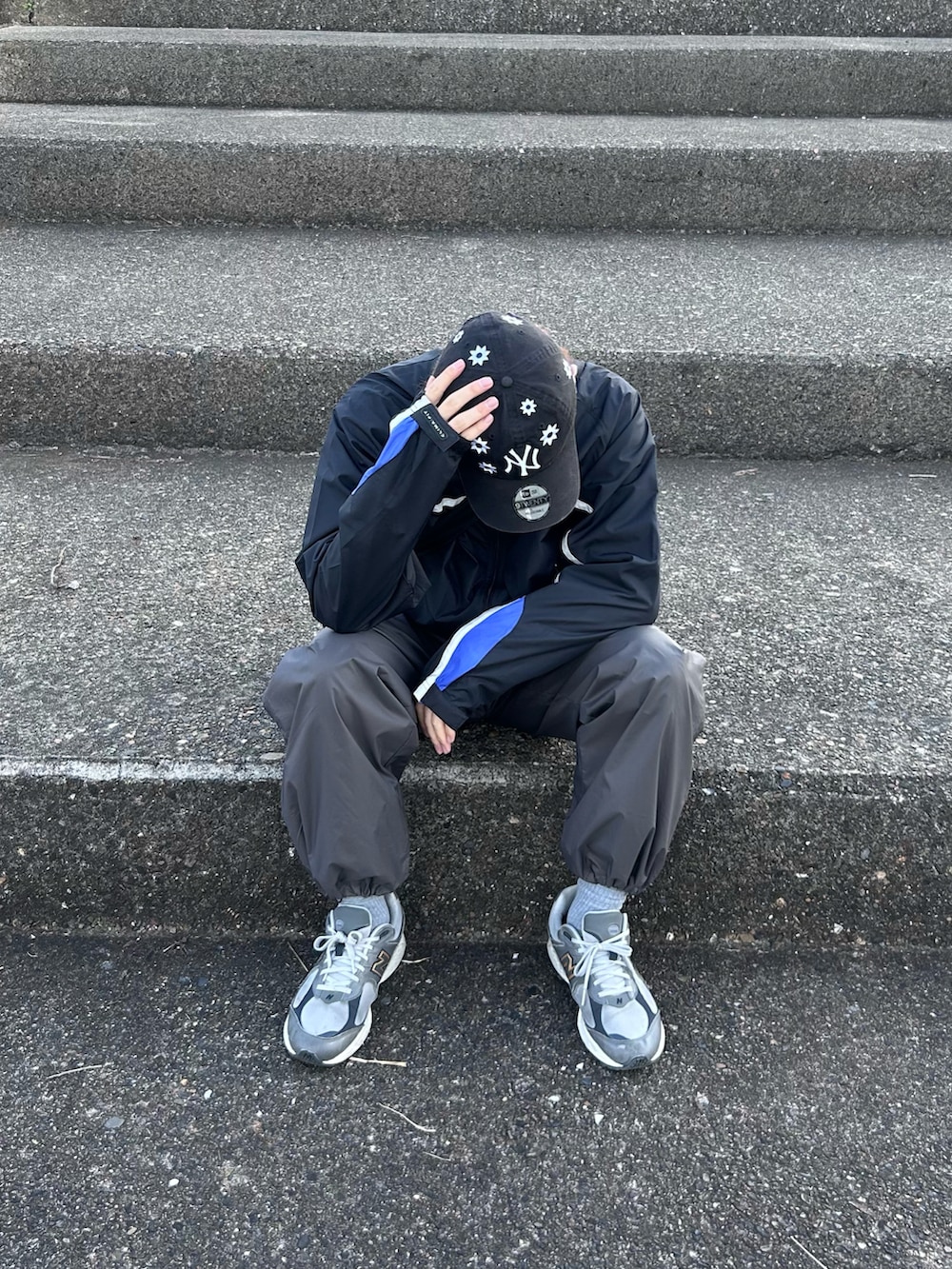 ブラック系のナイロンジャケット、グレー系のその他パンツ、グレー系のスニーカーを着用したメンズの春コーディネートの4枚目の写真