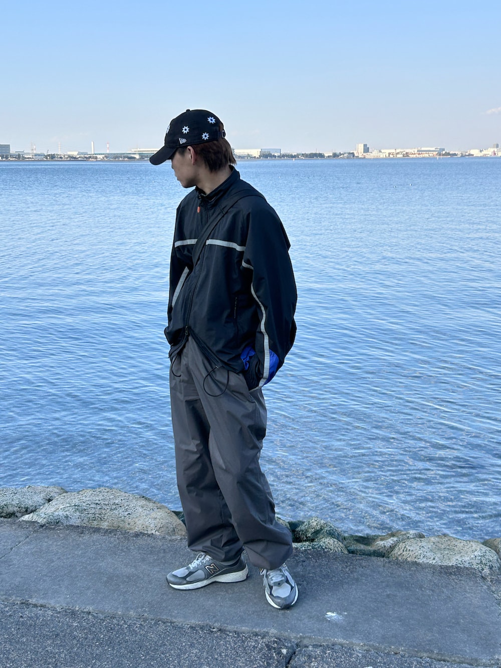 ブラック系のナイロンジャケット、グレー系のその他パンツ、グレー系のスニーカーを着用したメンズの春コーディネートの2枚目の写真