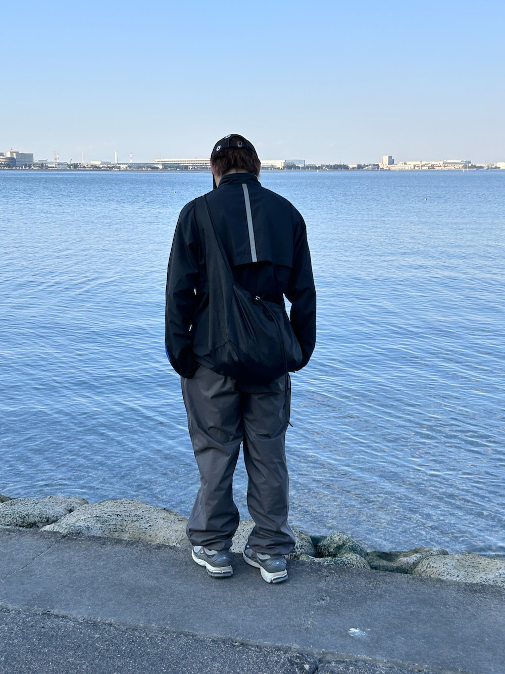 ブラック系のナイロンジャケット、グレー系のその他パンツ、グレー系のスニーカーを着用したメンズの春コーディネートの3枚目の写真