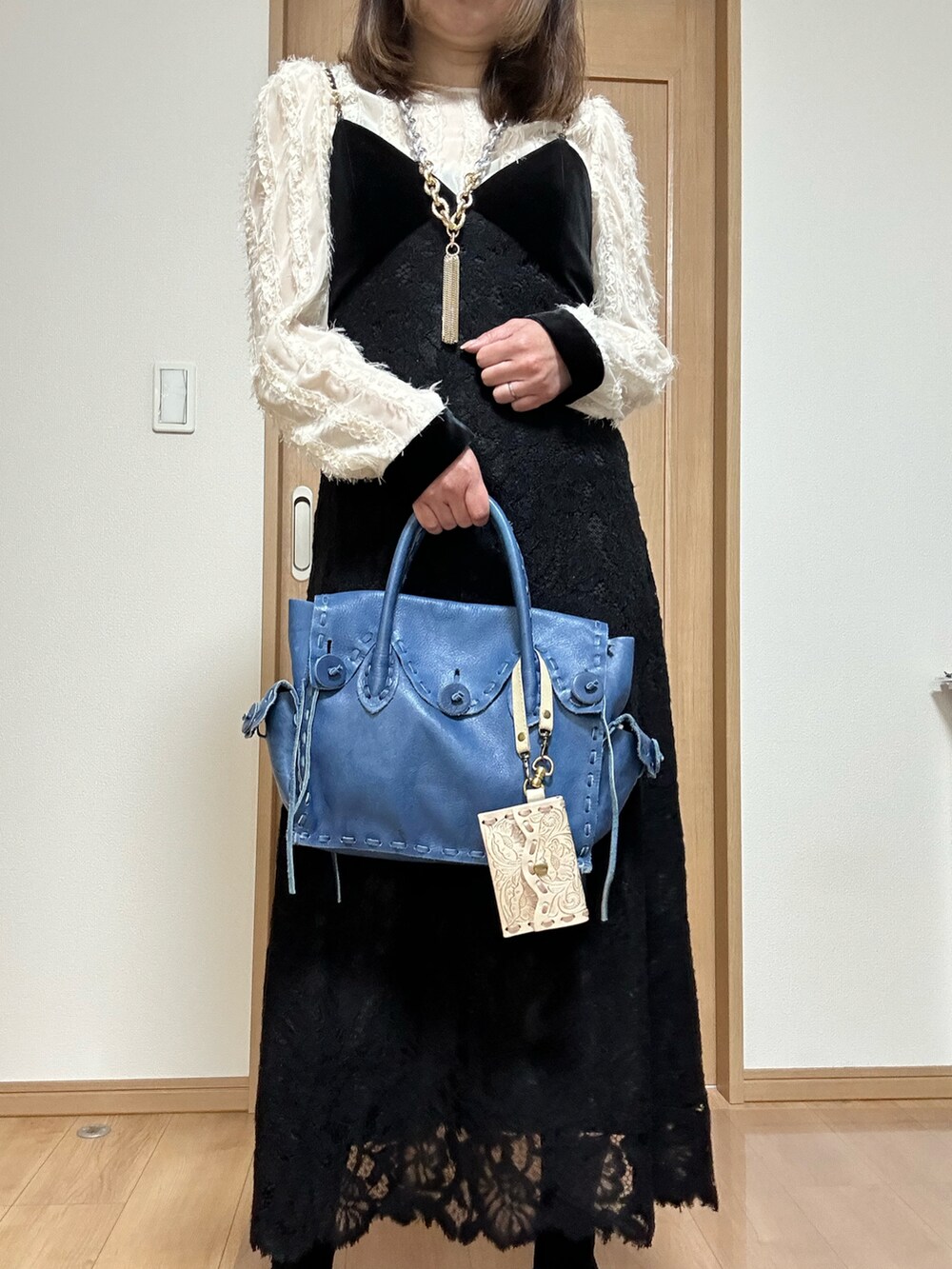 ブルー系のパンプス、ブラック系のワンピース、ブルー系のハンドバッグを着用したレディースの春コーディネートの5枚目の写真