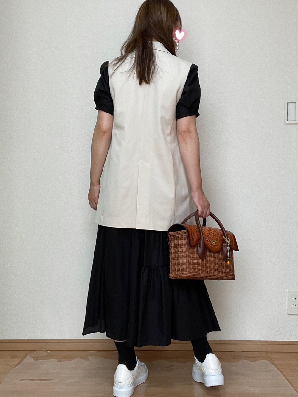 ベージュ系のベスト、ブラウン系のかごバッグ、ブラック系のワンピースを着用したレディースの夏コーディネートの3枚目の写真