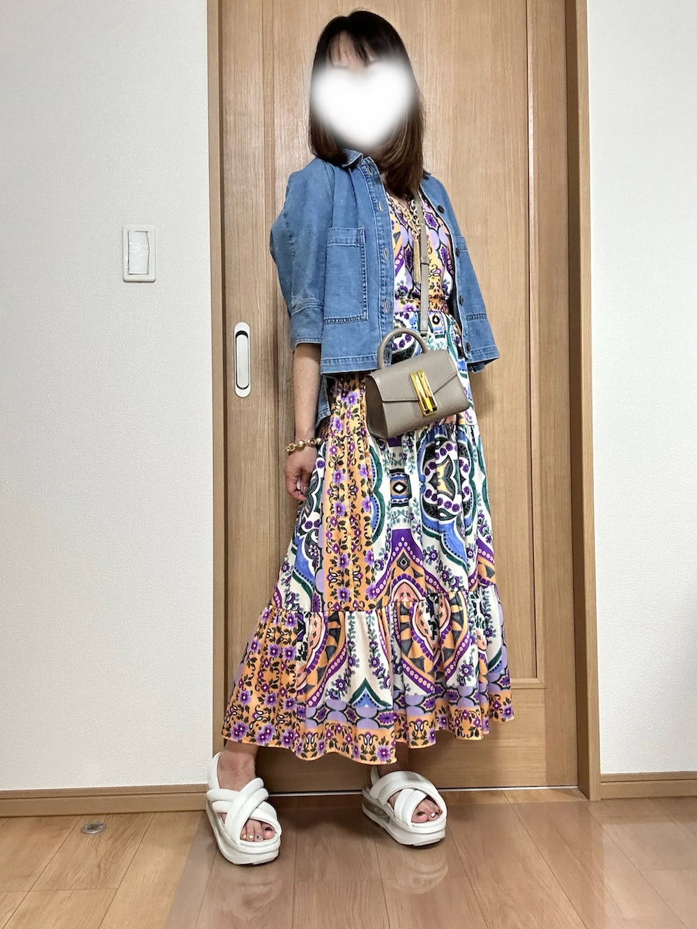 イエロー系のハンドバッグ、オレンジ系のワンピース、ブルー系のシャツ/ブラウスを着用したレディースの春コーディネートの2枚目の写真