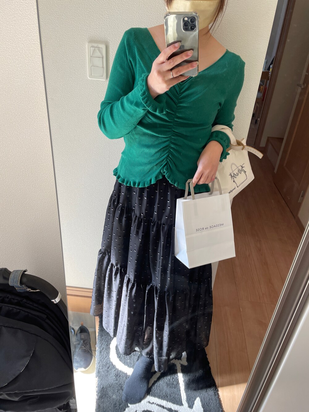 グリーン系のニット/セーター、ブラック系のスカートを着用したレディースの秋コーディネートの2枚目の写真