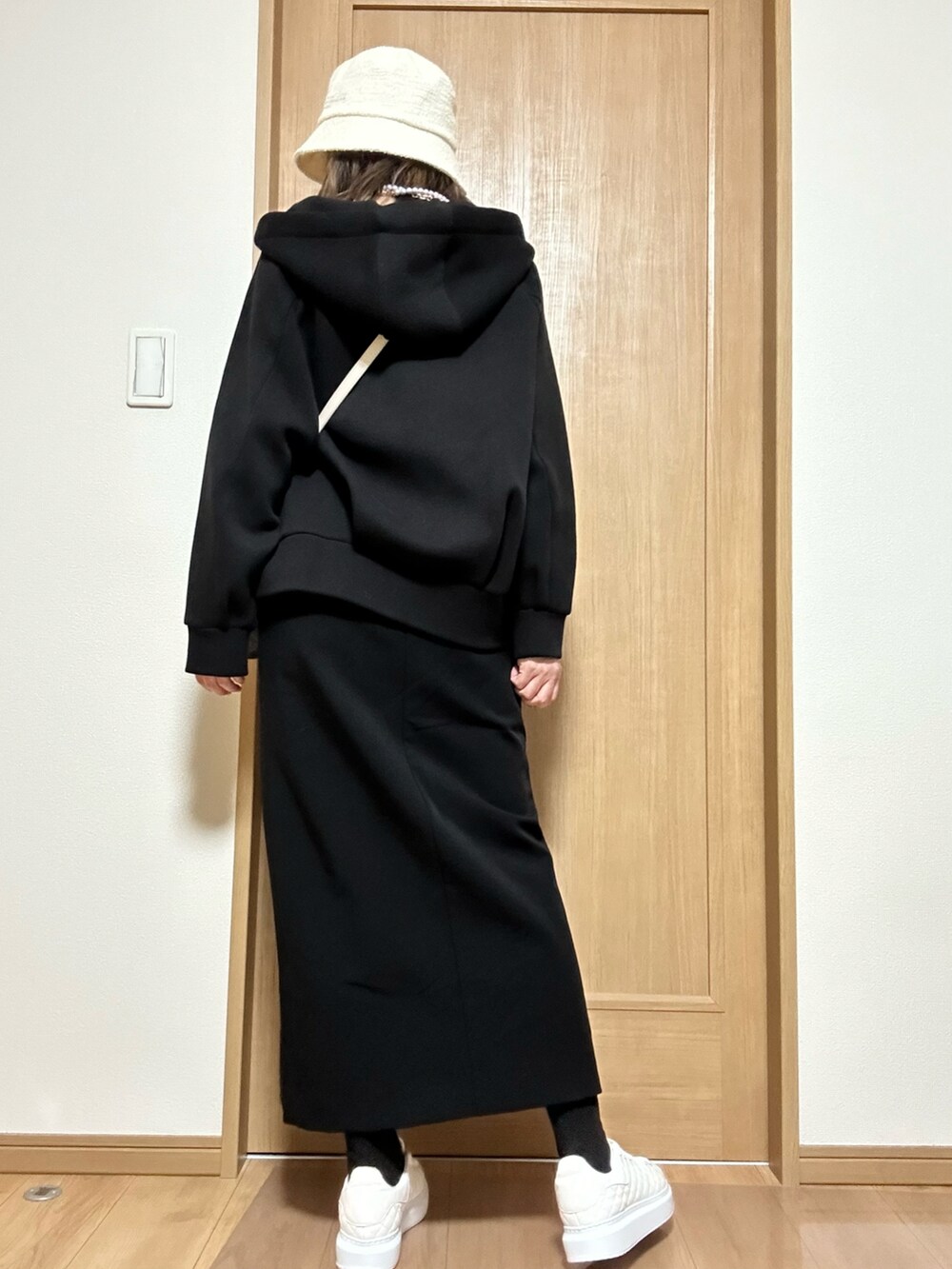 ホワイト系のバッグ、ブラック系のパーカー、ブラック系のスカートを着用したレディースの春コーディネートの3枚目の写真