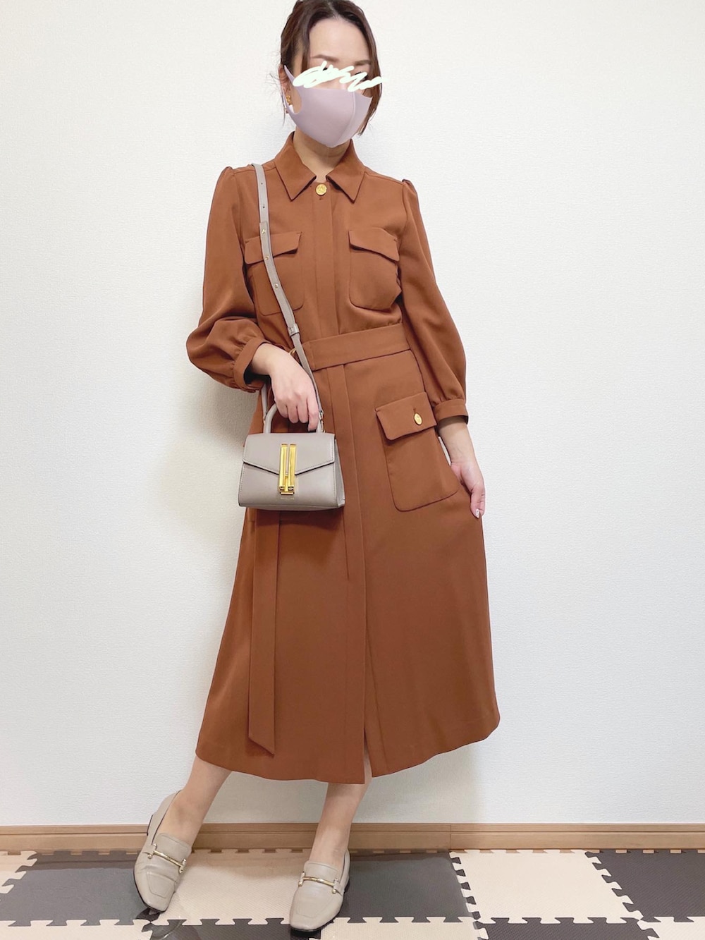 ブラック系のテーラードジャケット、ベージュ系のショルダーバッグ、ブラウン系のワンピースを着用したレディースの冬コーディネートの2枚目の写真