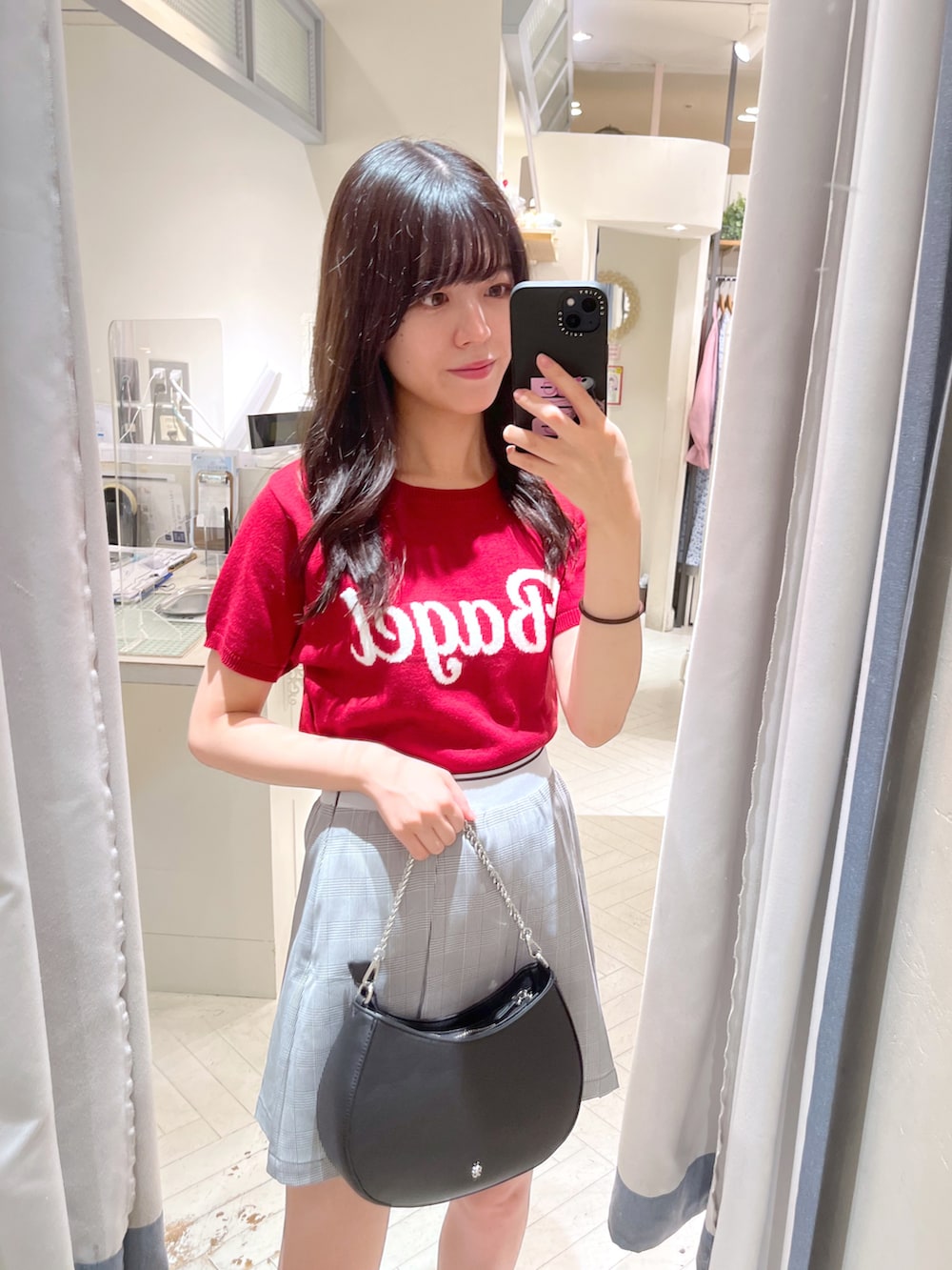 レッド系のニット/セーター、グレー系のスカート、ブラック系のショルダーバッグを着用したレディースの夏コーディネートの2枚目の写真