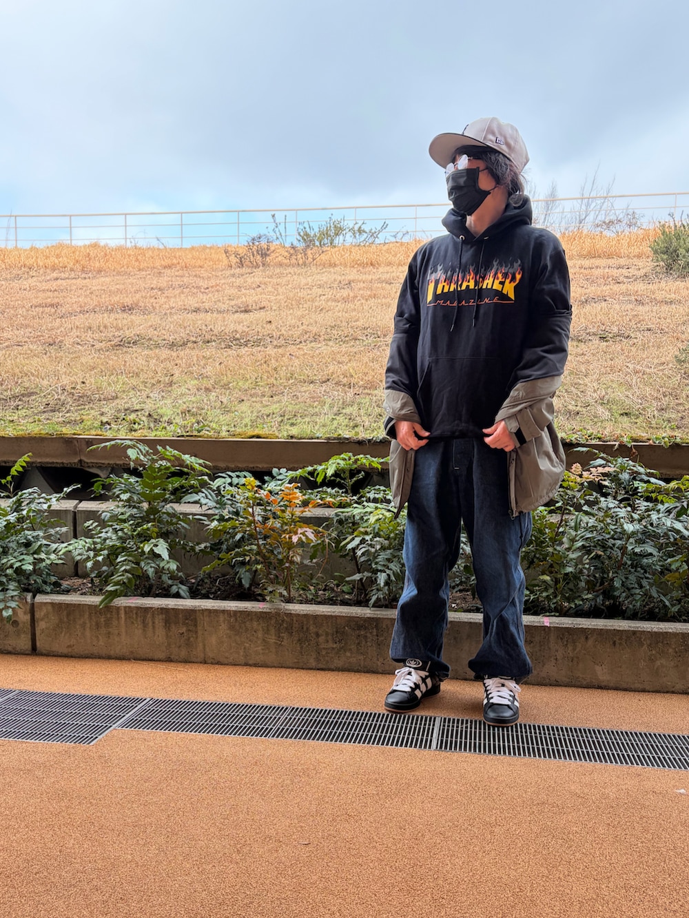 ブラック系のパーカー、グリーン系のナイロンジャケット、ブルー系のサロペット/オーバーオールを着用したメンズの春コーディネートの4枚目の写真