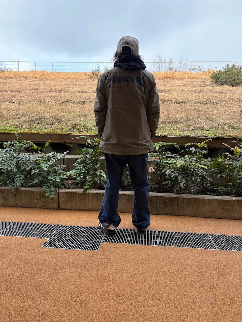 ブラック系のパーカー、グリーン系のナイロンジャケット、ブルー系のサロペット/オーバーオールを着用したメンズの春コーディネートの3枚目の写真