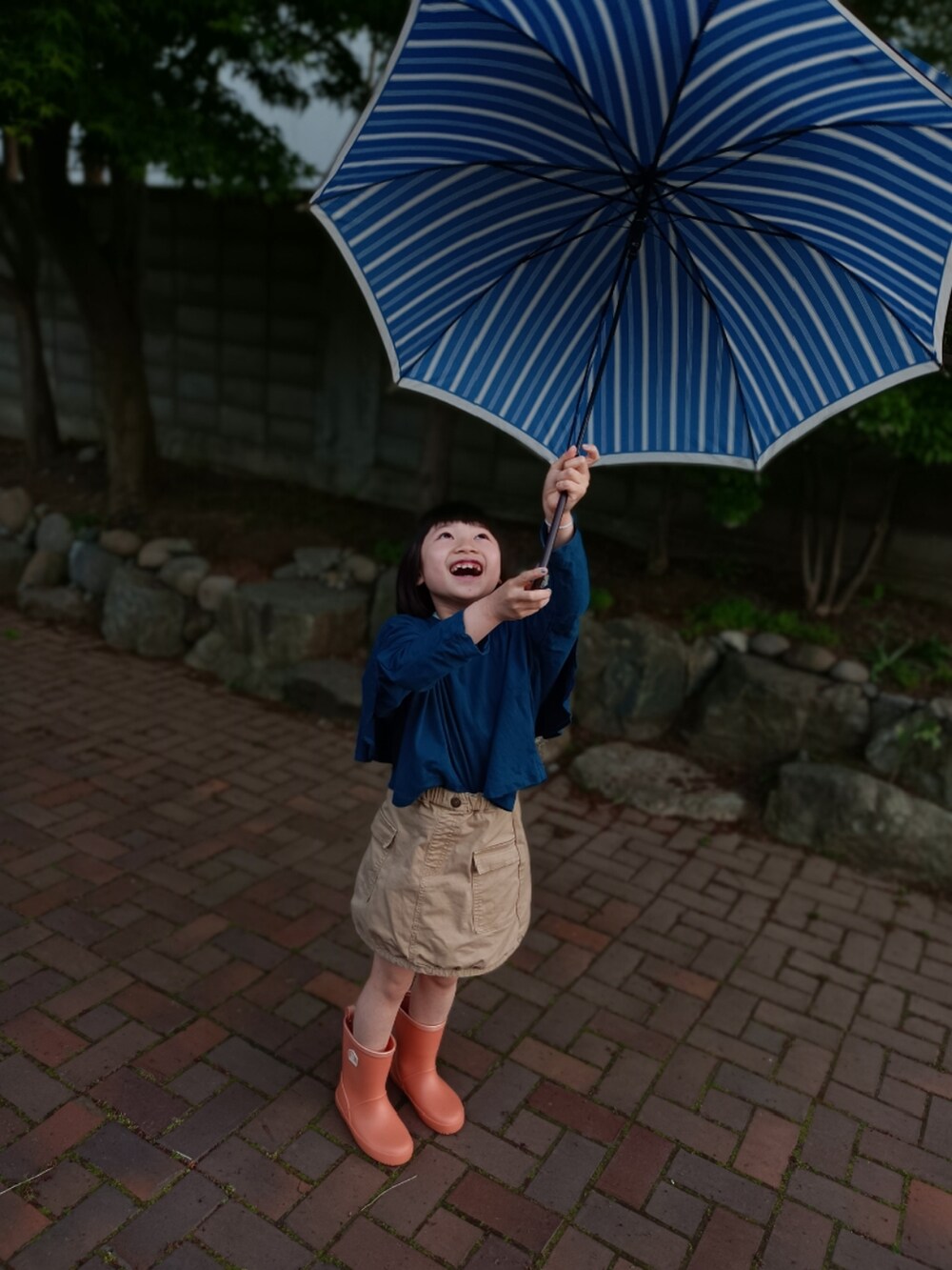 ブルー系のTシャツ/カットソー、ベージュ系のスカート、オレンジ系のレインシューズを着用したキッズの夏コーディネートの5枚目の写真