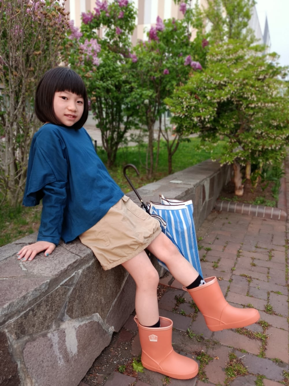 ブルー系のTシャツ/カットソー、ベージュ系のスカート、オレンジ系のレインシューズを着用したキッズの夏コーディネートの3枚目の写真