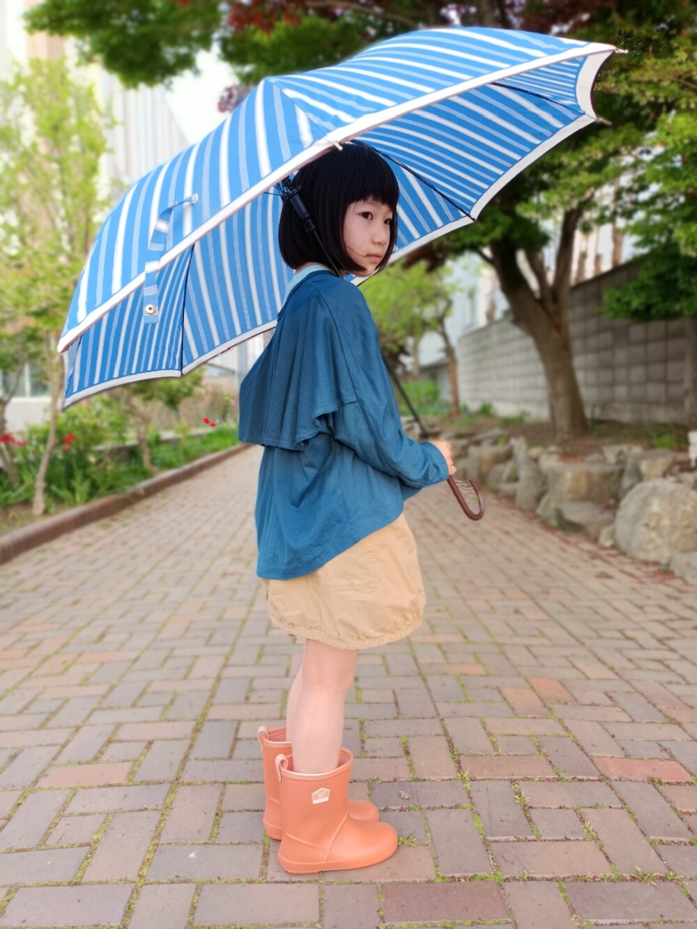 ブルー系のTシャツ/カットソー、ベージュ系のスカート、オレンジ系のレインシューズを着用したキッズの夏コーディネートの4枚目の写真