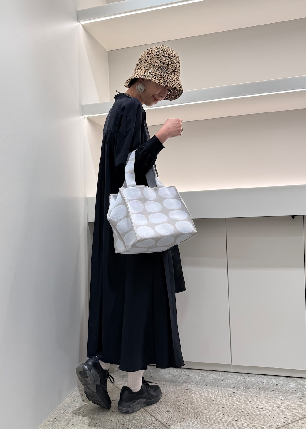 ブルー系のトートバッグ、ホワイト系のイヤリングを着用したレディースの春コーディネートの4枚目の写真