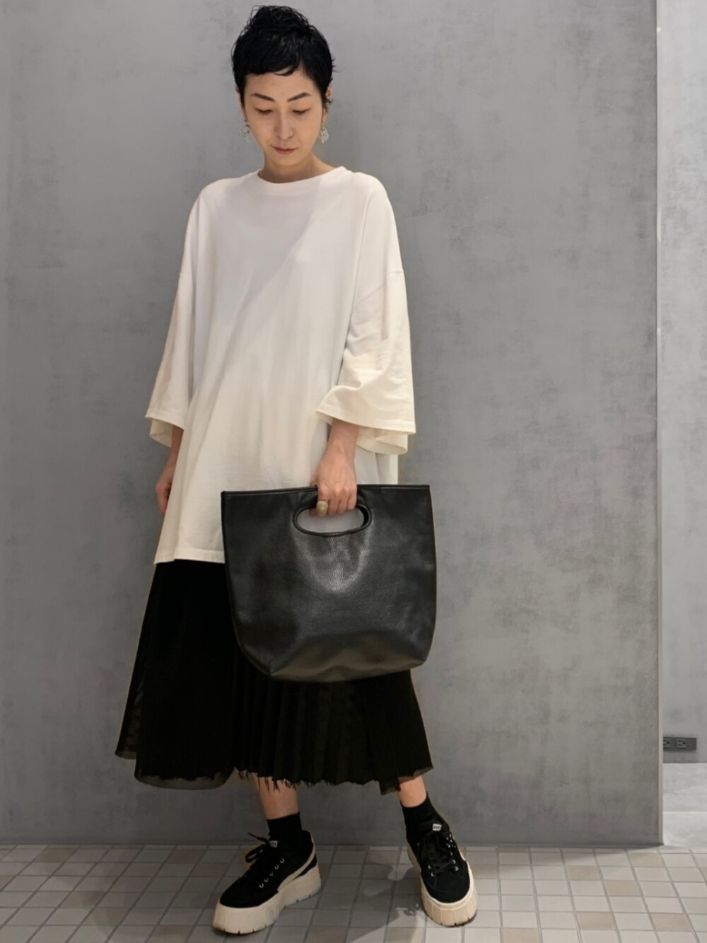 ブラック系のハンドバッグを着用したレディースの夏コーディネートの2枚目の写真