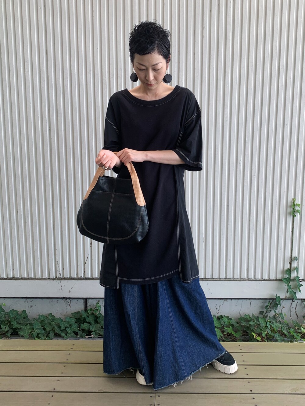 ブラック系のハンドバッグ、ブラック系のイヤリングを着用したレディースの夏コーディネートの2枚目の写真