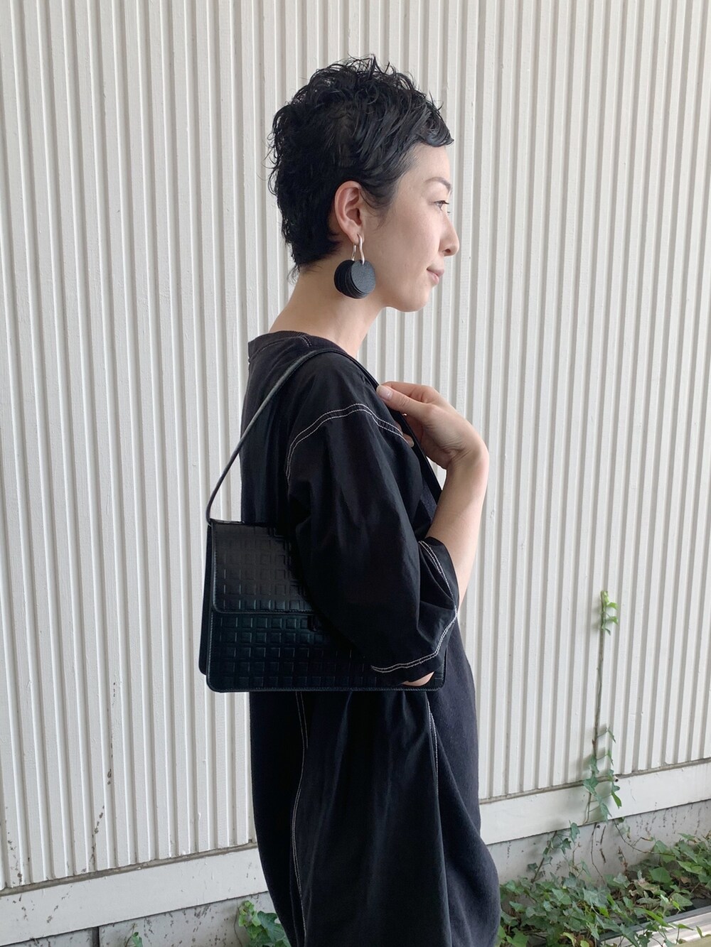 ブラック系のハンドバッグ、ブラック系のイヤリング、シルバー系のリングを着用したレディースの夏コーディネートの3枚目の写真