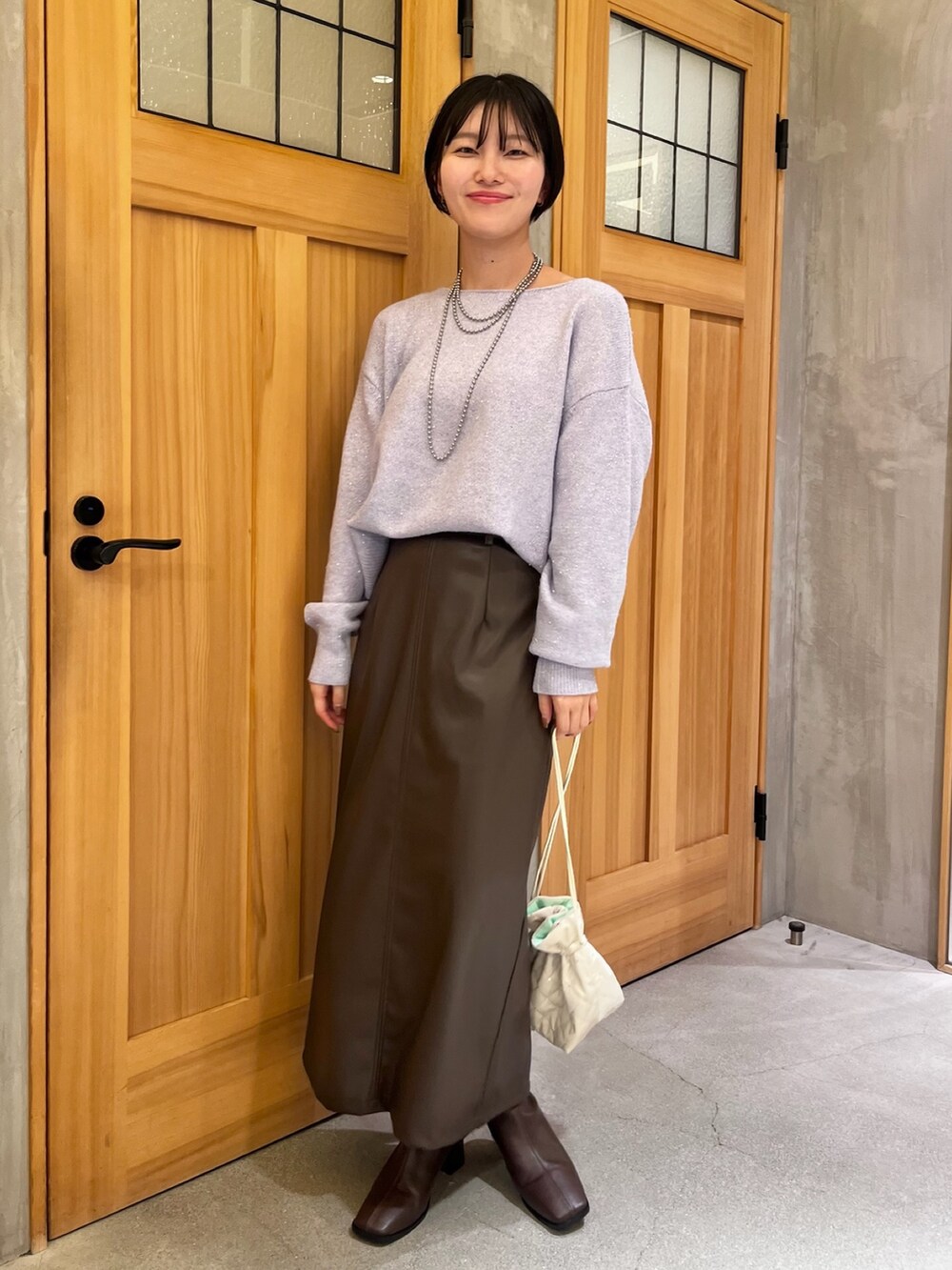 ホワイト系のその他アウター、パープル系のニット/セーター、ブラウン系のスカートを着用したレディースの冬コーディネートの3枚目の写真