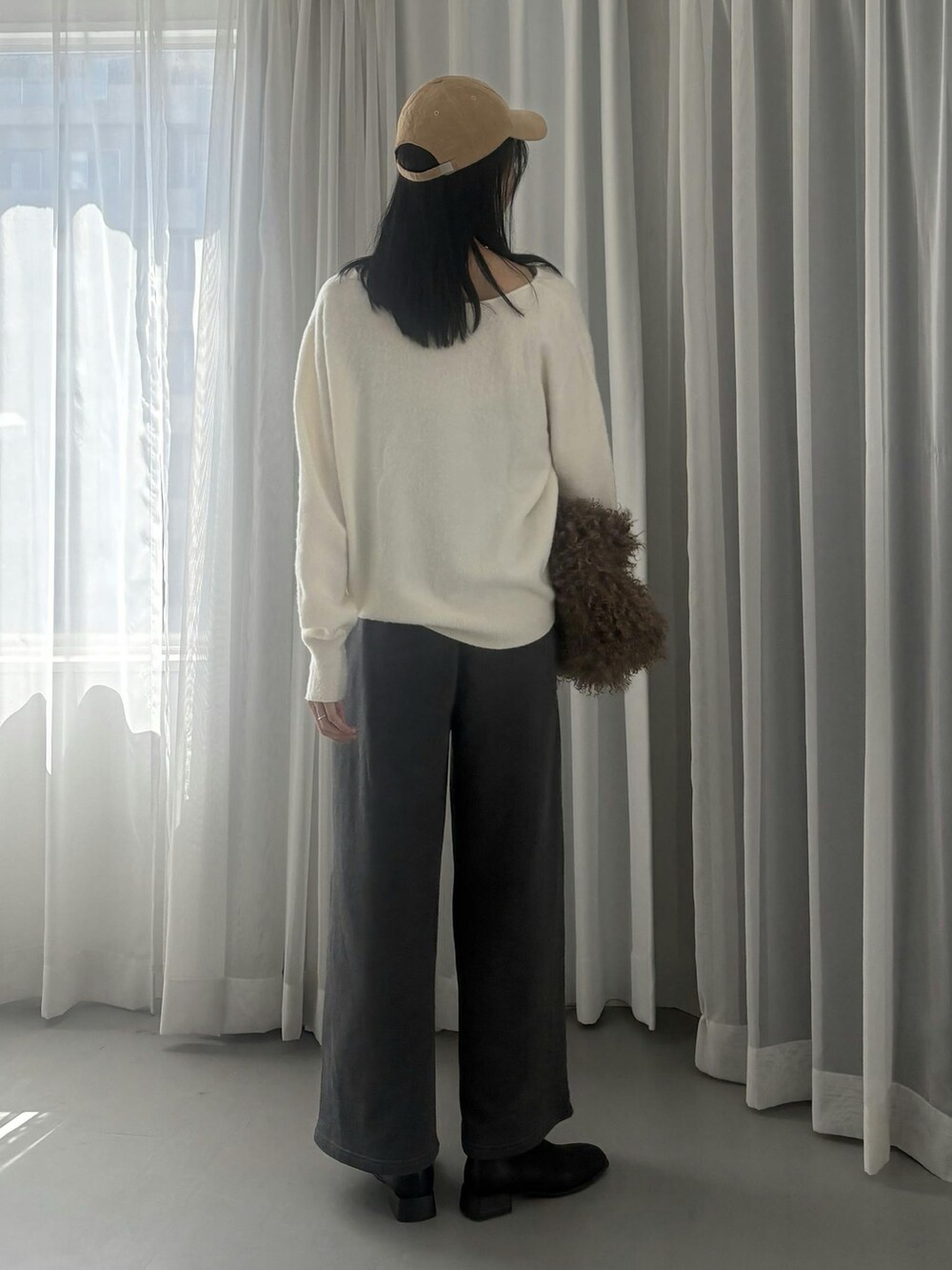 ホワイト系のニット/セーター、グレー系のスウェットパンツ、ベージュ系のキャップを着用したレディースの秋コーディネートの3枚目の写真