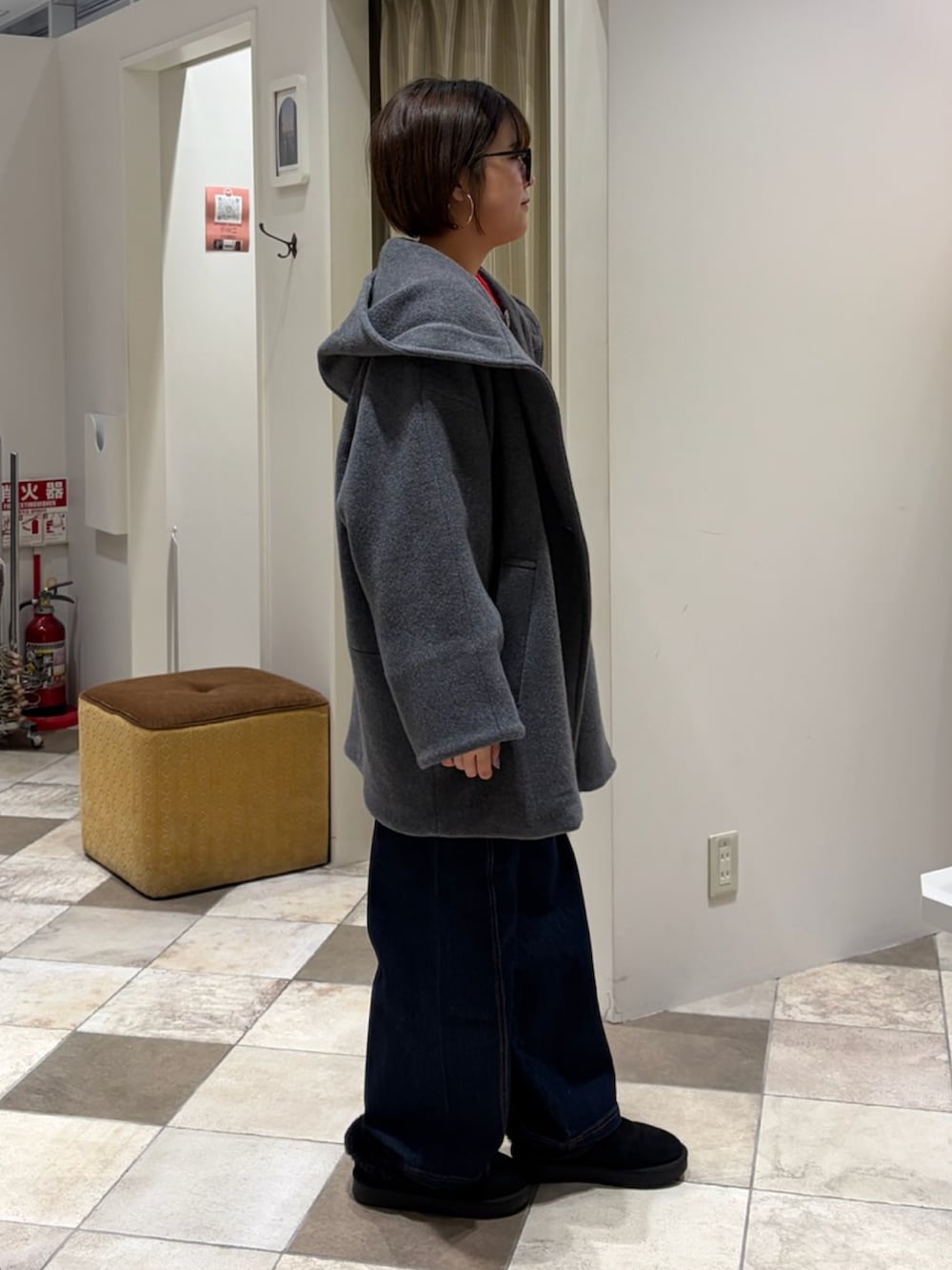 レッド系のニット/セーター、グレー系のその他アウター、ブルー系のデニムパンツを着用したレディースの冬コーディネートの2枚目の写真