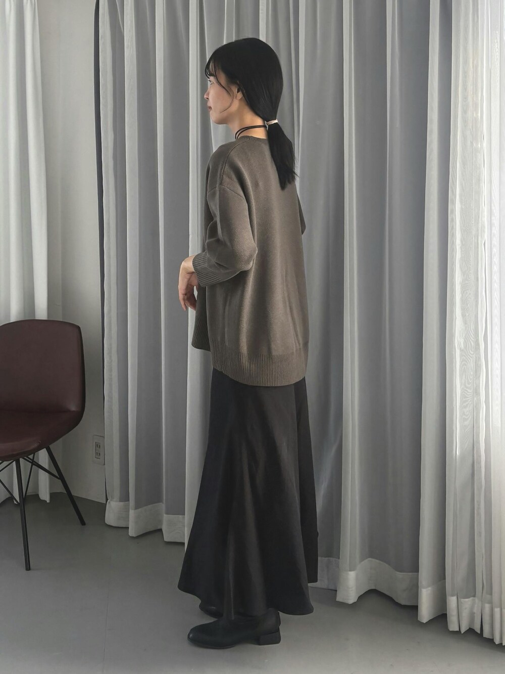 グレー系のニット/セーター、ブラック系のスカートを着用したレディースの秋コーディネートの2枚目の写真