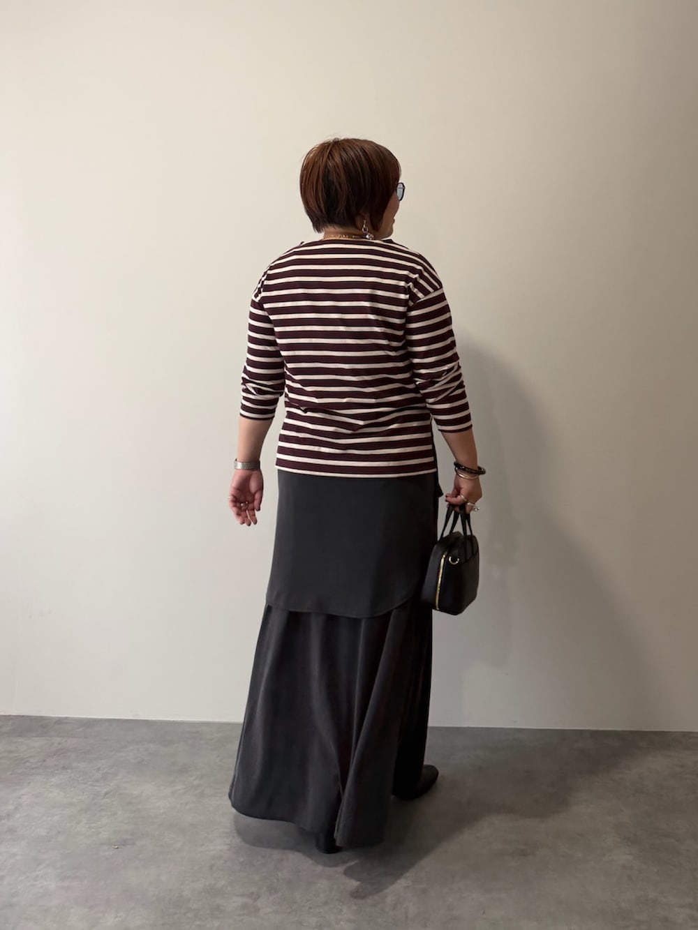 レッド系のTシャツ/カットソー、グレー系のシャツ/ブラウス、ブラック系のスカートを着用したレディースの秋コーディネートの3枚目の写真