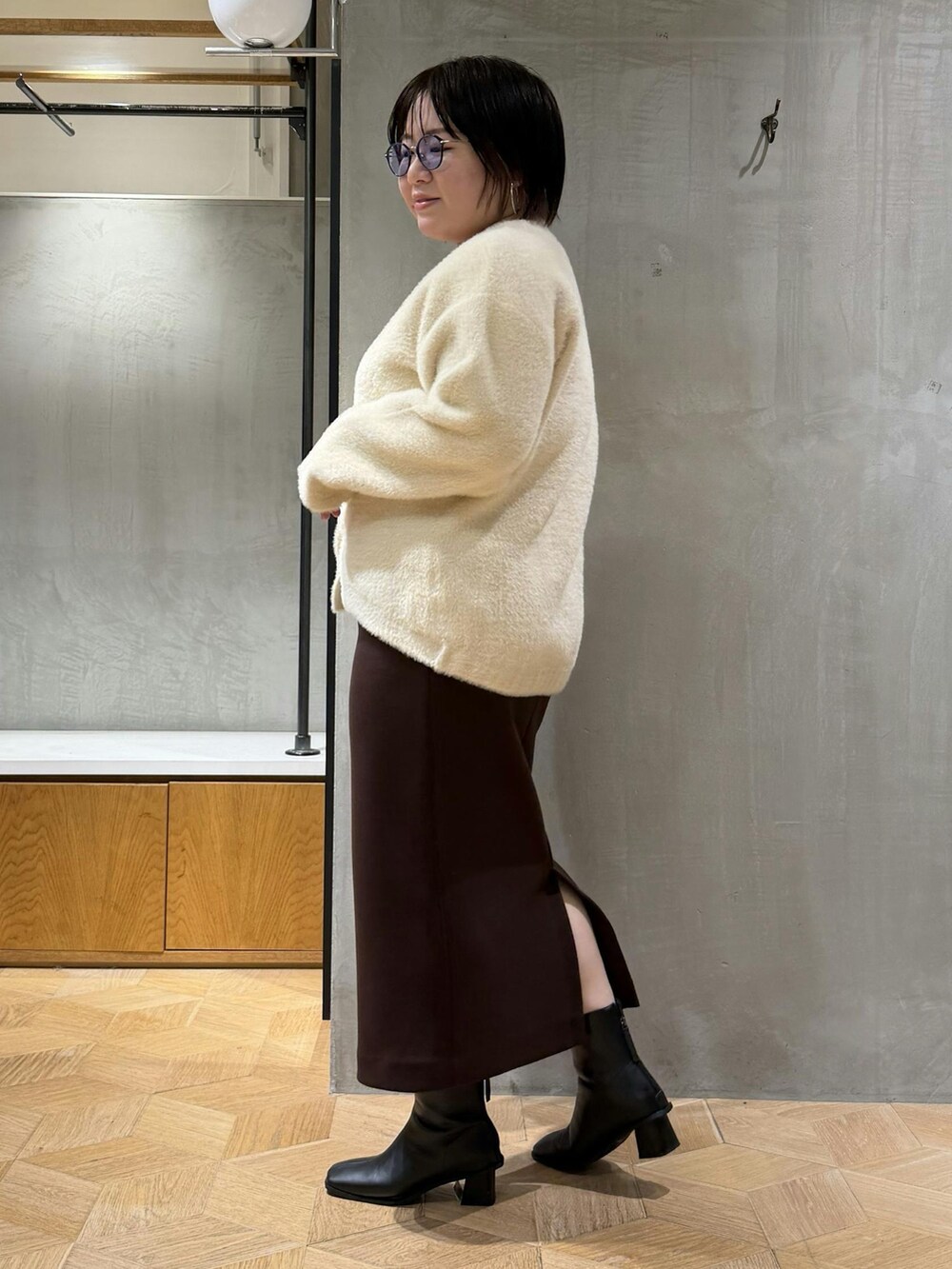 ホワイト系のカーディガン/ボレロ、ブラウン系のスカート、ブラック系のブーツを着用したレディースの秋コーディネートの2枚目の写真