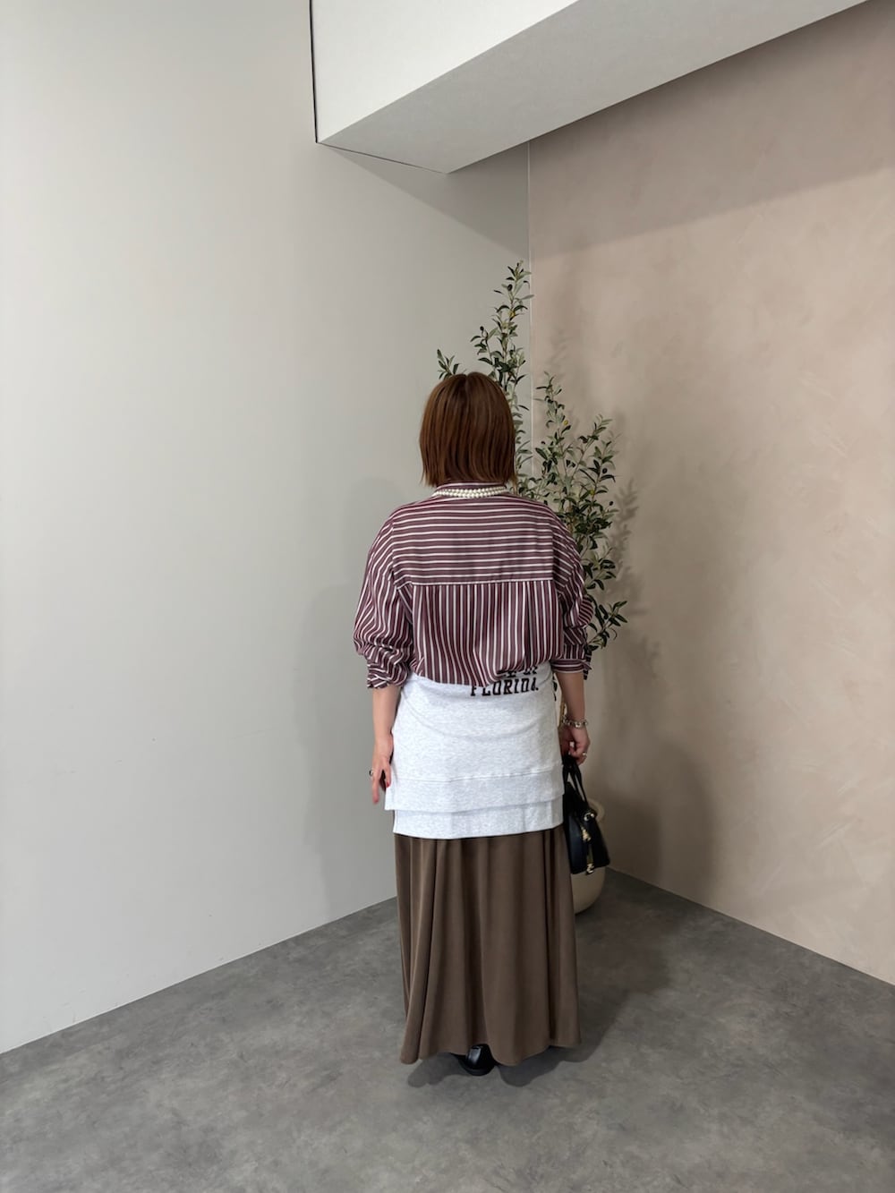 レッド系のシャツ/ブラウス、ベージュ系のスウェット、ブラウン系のスカートを着用したレディースの秋コーディネートの2枚目の写真