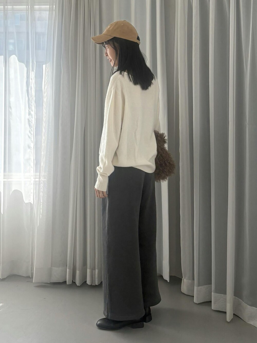 ホワイト系のニット/セーター、グレー系のスウェットパンツ、ベージュ系のキャップを着用したレディースの秋コーディネートの2枚目の写真