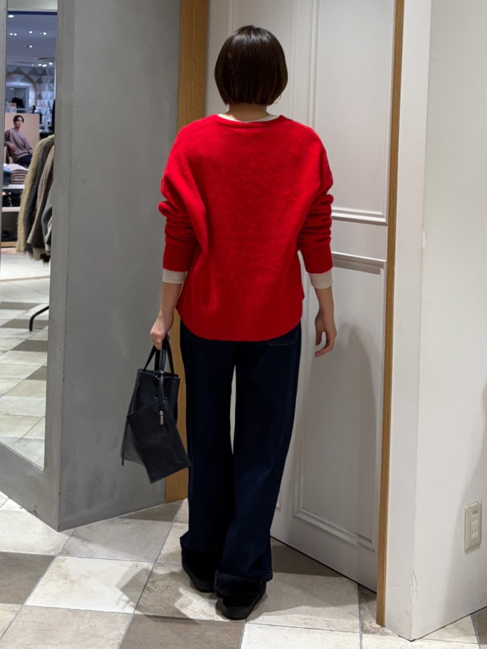 レッド系のニット/セーター、グレー系のその他アウター、ブルー系のデニムパンツを着用したレディースの冬コーディネートの6枚目の写真